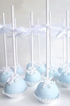 blue cake pops with white frosting and snowflakes on them