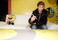 a man sitting on top of a white couch next to a spongebob pillow