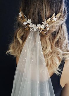 a woman wearing a veil with flowers and pearls on the back of her head is seen from behind