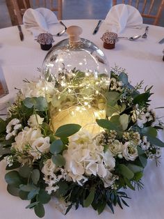 flowers and greenery sit under a glass dome on a table at a wedding reception