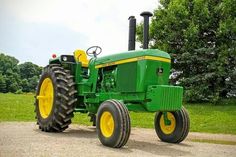 a green tractor parked on top of a dirt road