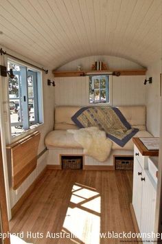 the interior of a tiny house with wood flooring and white walls, including windows