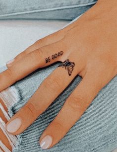 a woman's hand with a small butterfly tattoo on the ring finger that says be good