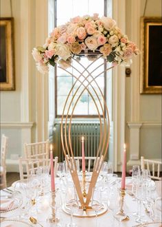 a centerpiece with candles and flowers on top of a table in a dining room