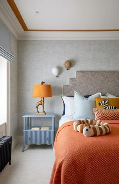 a bedroom with orange bedding and two lamps on either side of the headboard