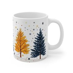 a white coffee mug with trees painted on the side and snow flakes all over it