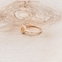 a yellow diamond ring sitting on top of a piece of wood