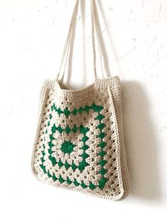 a crocheted bag hanging from a hook on a white wall with green accents