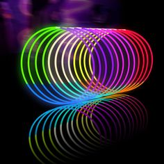 an image of neon colored circles in the dark with reflections on the floor and black background