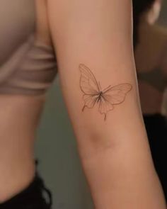 a woman's arm with a small butterfly tattoo on the left side of her arm