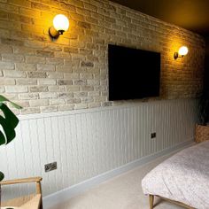 a bedroom with brick walls and white bedding has a flat screen tv on the wall