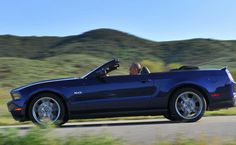 a blue convertible car driving down the road