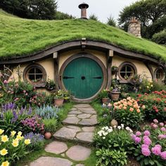 a green hobbot house surrounded by flowers and greenery