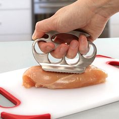 a person is using a knife to cut up some fish on a cutting board with red scissors