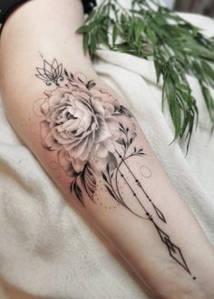 a woman's arm with a flower and arrow tattoo on the left side of her leg