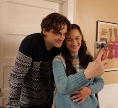 a man and woman taking a selfie in front of a door with their cell phone