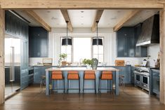 a kitchen with blue cabinets and orange chairs in the center, along with an island