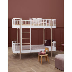 a white bunk bed sitting on top of a wooden floor next to a pink wall