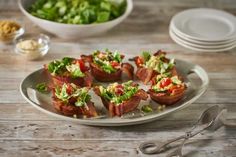 bacon wrapped in lettuce on a plate next to bowls of salad and utensils