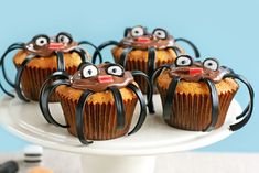 some cupcakes with chocolate icing and googly eyes are on a cake plate