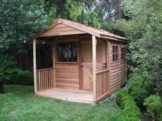 a wooden shed sitting in the middle of a lush green field