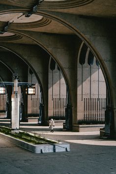 a person riding a skateboard in an empty parking lot next to tall arches and windows