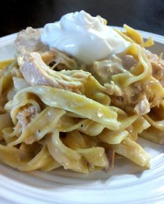 a white plate topped with pasta and meat covered in sauce next to a whipped cream