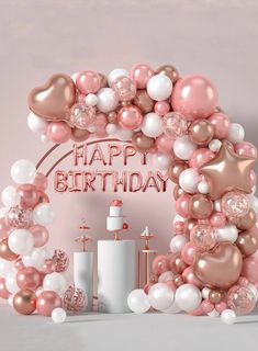 a pink and white birthday arch with balloons