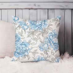 a white and blue floral pillow sitting on top of a furnishing area next to a wooden headboard