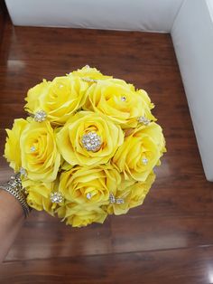 a bouquet of yellow roses is being held by someone's hand on the floor