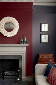 a living room filled with furniture and a fire place in front of a red wall