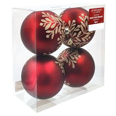 three red christmas balls in a clear box with gold trimmings on each ornament