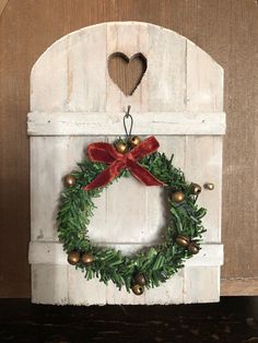 a christmas wreath hanging on the side of a white door with bells and a red bow