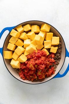 a pot filled with lots of food on top of a white counter next to a blue spatula