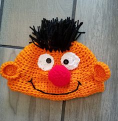 an orange knitted hat with black hair on top of a wooden floor next to a tile floor