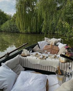 a boat filled with lots of pillows on top of a river next to a lush green forest