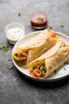 two burritos on a white plate with sauce