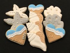 decorated cookies in the shape of seashells and starfish on a black background