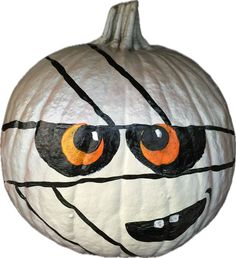 a white pumpkin with orange eyes and black lines painted on it's face is shown