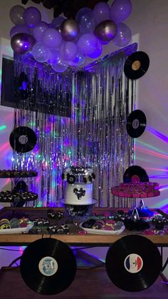 a table topped with lots of black and white records, balloons and disco balls hanging from the ceiling