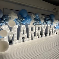 a large marquee sign with balloons on the wall behind it that says marry