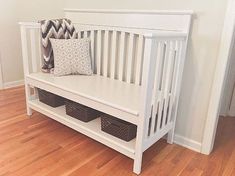 a white crib with two baskets underneath it and a pillow on the top shelf