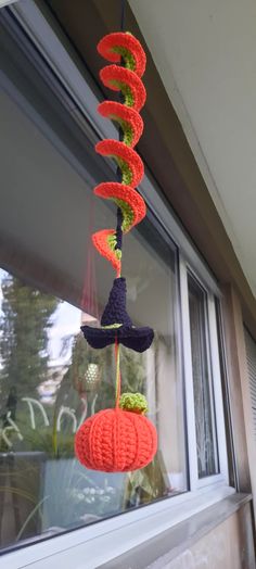 crocheted hats hanging from a window sill in front of a building with windows