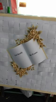 an open book is sitting on top of a white basket with gold flowers and leaves