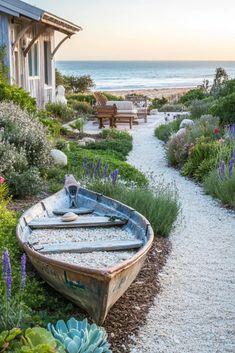 a boat sitting on top of a gravel road next to a lush green field filled with flowers