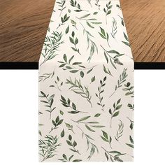 an image of a table runner with green leaves on it and wood flooring in the background