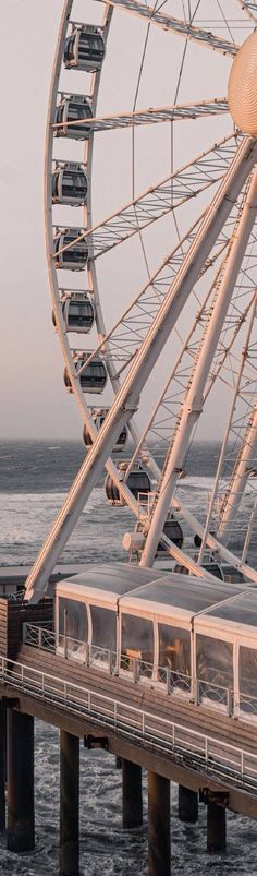 a ferris wheel sitting on top of a pier next to the ocean