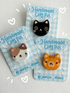 two handmade clay pins with cats on them