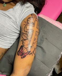 a woman with a cross and butterfly tattoo on her arm