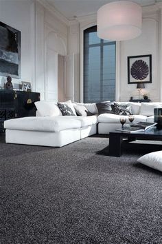 a living room filled with lots of white furniture and black rugs on the floor